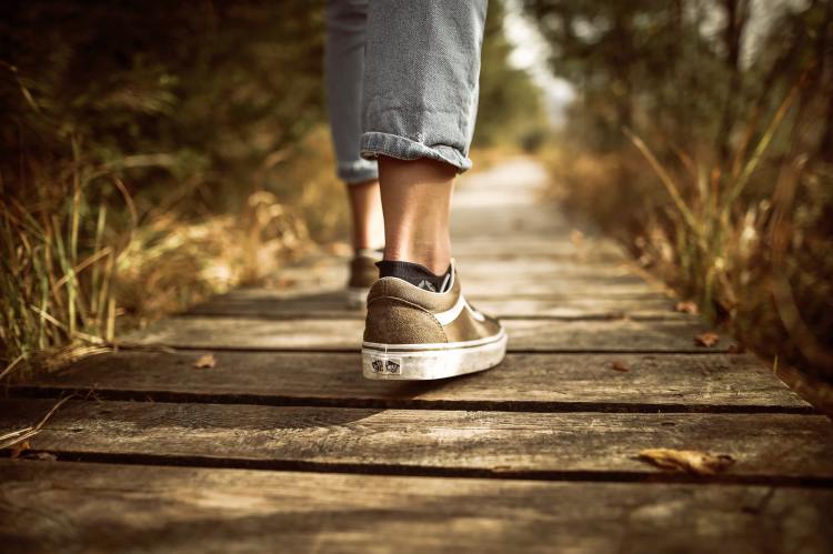 View of a woman's tennis shoes walking down a boardwalk
