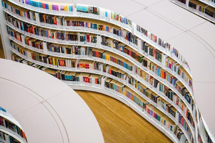 Curved white bookshelves in a library filled with colorful books